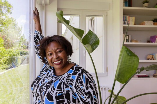 Woman smiling near window with indoor plant