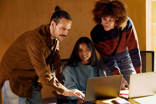 Team Collaborating Around Laptop in Modern Workspace