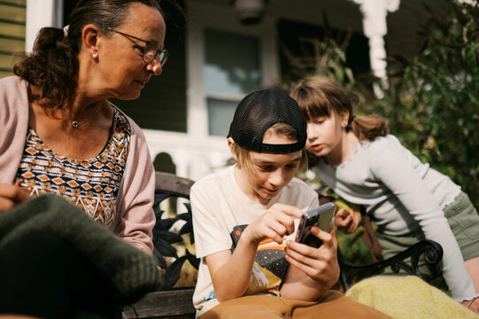 grandmother and grandchild sitting in yard looking at phone