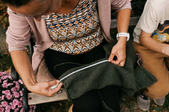 up close of woman knitting outdoors on bench