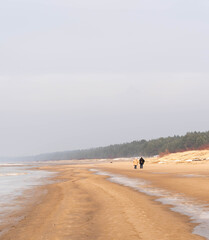 People walking along wide sandy Baltic Sea beach in Lilaste Latvia
