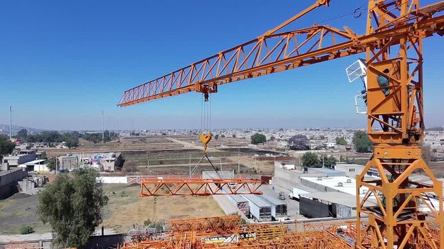 Vista a&eacute;rea detallada que captura la precisi&oacute;n de una gr&uacute;a torre industrial mientras mueve una secci&oacute;n de armaz&oacute;n met&aacute;lico (parte de la pluma o flecha)