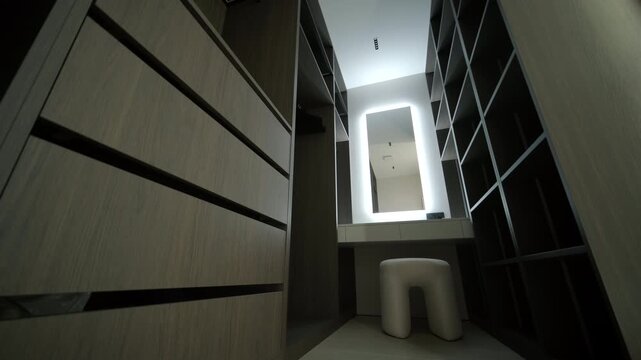 Modern minimalist walk-in wardrobe with wooden shelves and LED lighting.
