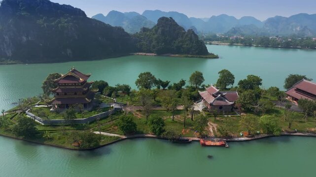 Aerial view of Chua Vang Pagoda, a popular destination for tourists and pilgrims, located in Ninh Binh, Vietnam. Mountains in the background.