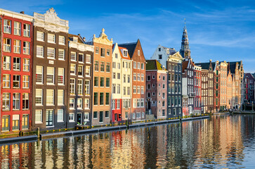 Obraz premium Historic buildings on Damrak canal in Amsterdam, Netherlands on a sunny day