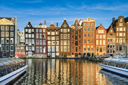 Historic buildings on Damrak canal in Amsterdam, Netherlands on a sunny day