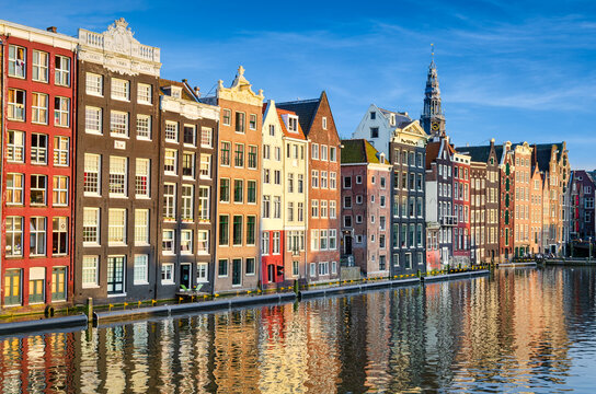 Historic buildings on Damrak canal in Amsterdam, Netherlands on a sunny day