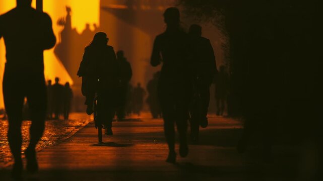 Anonymous crowd silhouettes walking in city underpass at sunset