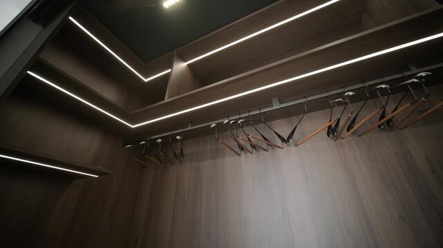 Modern minimalist walk-in wardrobe with wooden shelves and LED lighting.