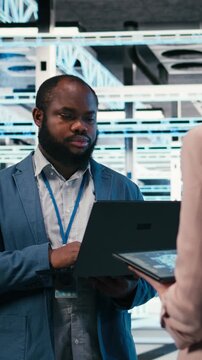 Vertical video Data center team of technicians uses AI deep learning on devices to optimize performance. Software developers brainstorm how to integrate neural network automation in data center