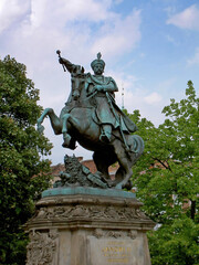 Obraz premium Equestrian statue of King John III Sobieski in Gdansk surrounded by green trees. Historical monument and famous landmark in Poland.