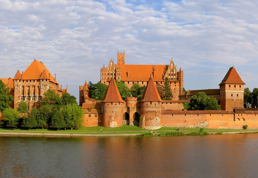 Summer view of the Malbork Castle across the Nogat river. Iconic Polish landmark and historical Teutonic fortress.