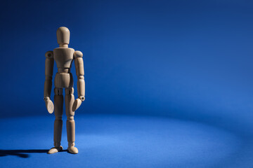 One wooden mannequin standing on blue background, space for text