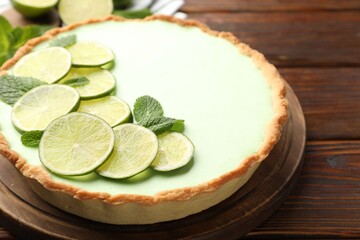 Tasty lime pie with fruit slices and mint leaves on wooden table, closeup © New Africa