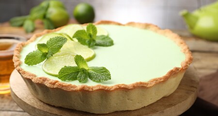 Tasty lime pie with fruit slices and mint leaves on wooden table, closeup © New Africa