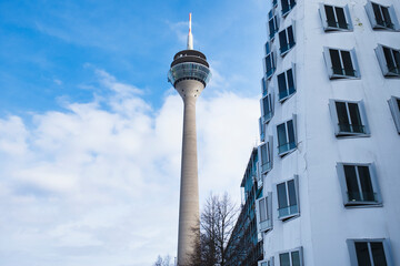 Obraz premium Rheinturm Düsseldorf TV Tower framed by modern residential building under blue sky in Germany 