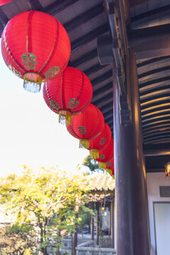 A row of red lanterns hang from a building. The lanterns are hanging from the ceiling and are red in color