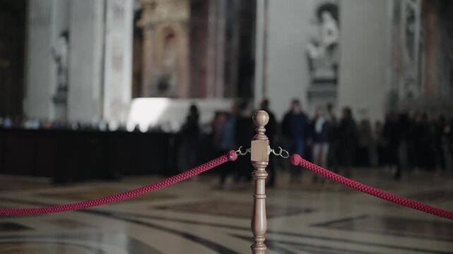 Rope barrier with wooden stanchion inside Saint Peter Church in Vatican, Rome, Italy. Preventing tourist from unautorized acces