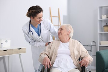 Obraz premium Care worker supporting senior woman in wheelchair indoors
