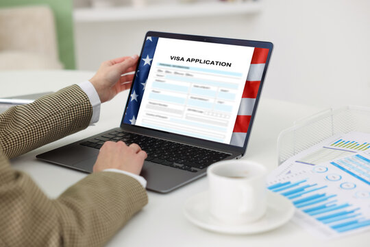 Woman using laptop to fill in online visa application form at table, closeup