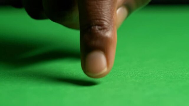 A close-up shot of a person's finger touching a vibrant green felt surface.