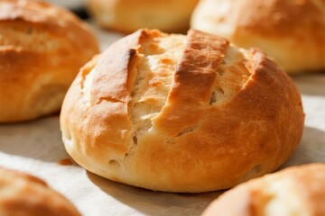 Freshly baked golden-brown bread rolls with a cracked crust, arranged on parchment paper.