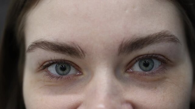 Young woman with beautiful eyes on grey background, closeup