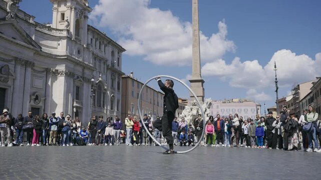 Big hula hoop artistic performer having performance on Navona square with crowd of tourist people spectators, cinematic selective focus isolated slow motion shot