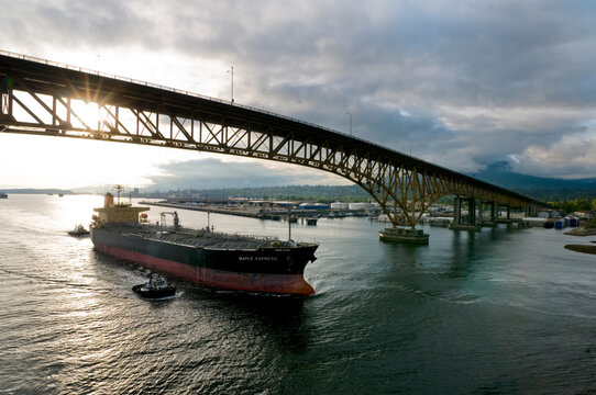 Canada, BC, Vancouver.  Freighter is escorted under the Second Narrows bridge on the Burrard Inlet by harbour tugs.