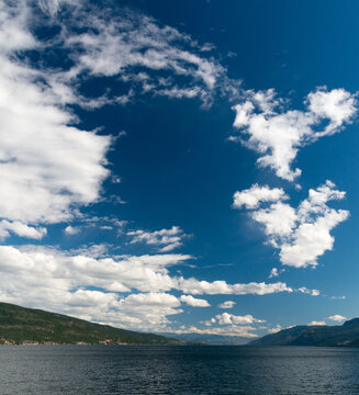 Canada, BC, Vernon.  White clouds and deep blue sky over Okanagan Lake.