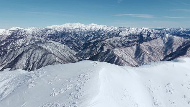 日本百名山の荒島岳　雪山ドローン映像　山頂に佇む登山者とアルプスの山々