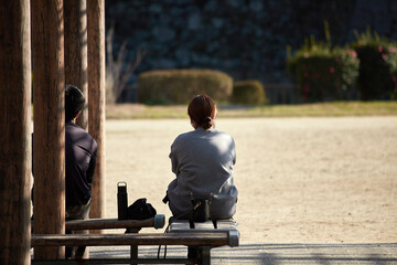春の公園のベンチで休憩する男女夫婦の姿
