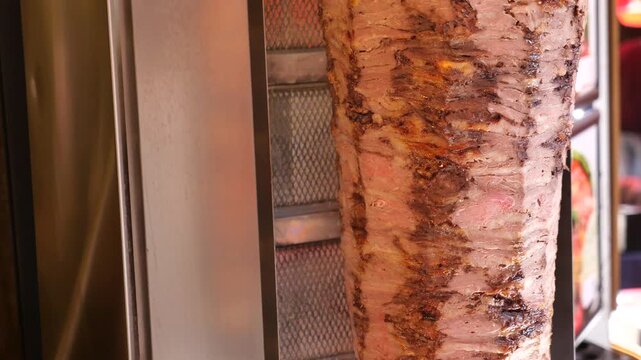 Chef slicing delicious shawarma meat from vertical rotisserie in fast motion