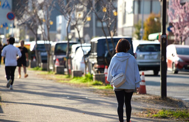 春の名城公園で散歩する中年女性とランニングする男性の姿