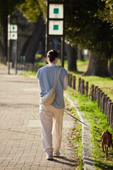 春の名城公園で犬を連れて散歩する若い女性の姿