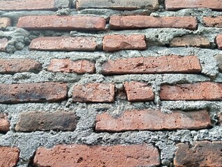Naklejka premium red brick wall that has not been coated with cement and painted behind the house