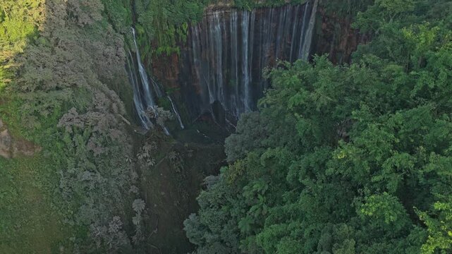 Aerial footage descending into the majestic canyon of tumpak sewu waterfall, surrounded by a lush tropical jungle in east java, indonesia