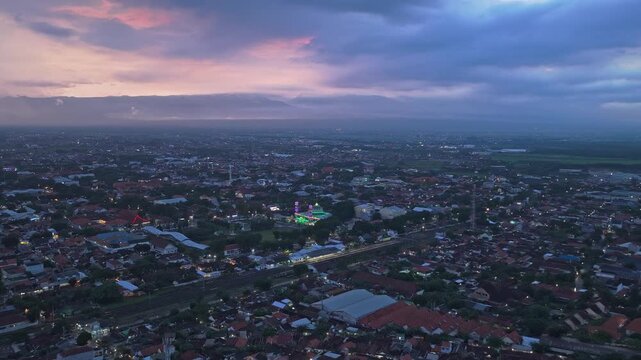 Aerial perspective over the city of probolinggo in east java, indonesia. The cityscape lights are turning on under a cloudy sunset sky
