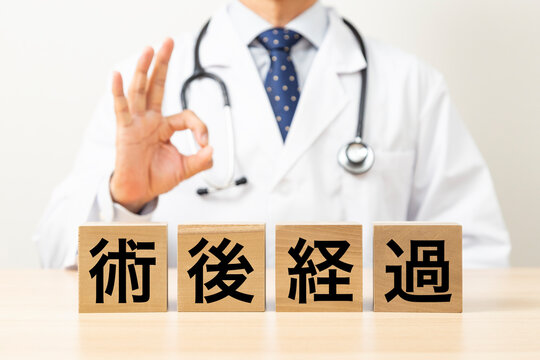 「術後経過」と書かれたブロックとOKサインをする医師