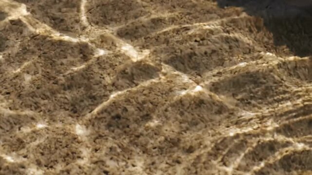 Sunlit water caustics ripple across sandy seabed, abstract natural texture for summer travel backgrounds, calm coastal mood, ocean light pattern for relaxation