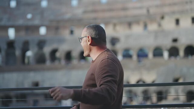 Positive sightseeing men show excitement emotions having fun on visit of Colosseum arena in Rome dancing and jumping in slow motion, cinematic selective foruc isolated shot