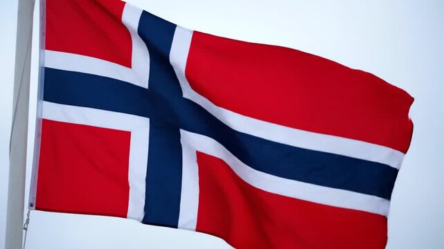 Norwegian flag waving in the wind on a flagpole against a clear sky