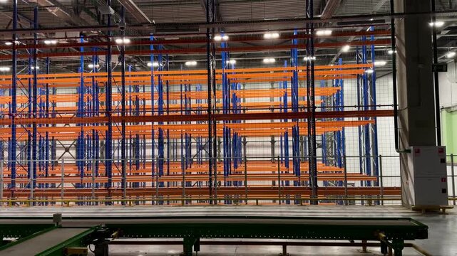 High angle view of a large warehouse with tall blue pallet racking systems. Industrial logistics facility featuring organized storage zones, numbered aisles and goods ready for distribution.