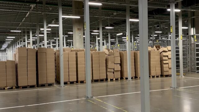 Large stacks of brown cardboard boxes on wooden pallets in a modern warehouse. Industrial storage facility for wholesale, e-commerce fulfillment and global shipping logistics background.