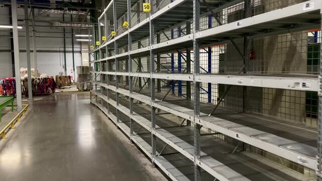 Wide interior of a modern industrial warehouse featuring empty numbered shelving units and recycling bales. Organized logistics facility for efficient storage, distribution and waste management.