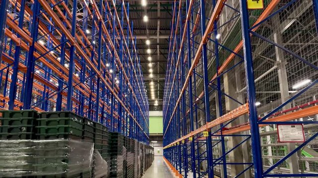 Low angle view of modern warehouse pallet racking system with blue metal frames. Organized industrial storage section with numbered aisles for efficient logistics, distribution and supply chain.