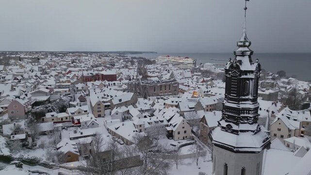 Aerial Flight Past Visby Cathedral Tower Toward Stora Torget and St Karin Ruin in Winter, Snow-covered Old Town, Gotland Sweden
