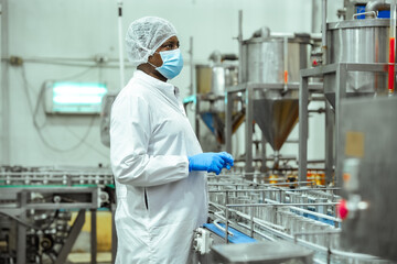 Naklejka premium Food safety supervisor observes canned seafood production line monitors empty metal containers on conveyor system inside processing plant, HACCP compliance contamination prevention standards.