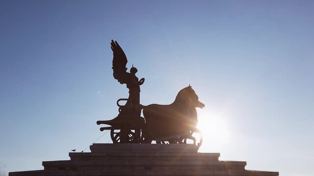 The quadriga statue dedicated to the freedom of citizens on the terrace of the Vittoriano called Altare della patria in Rome, Italy at sunset