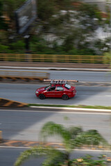 Obraz premium Red Fiat Siena side profile in motion, Compact work sedan driving on city avenue